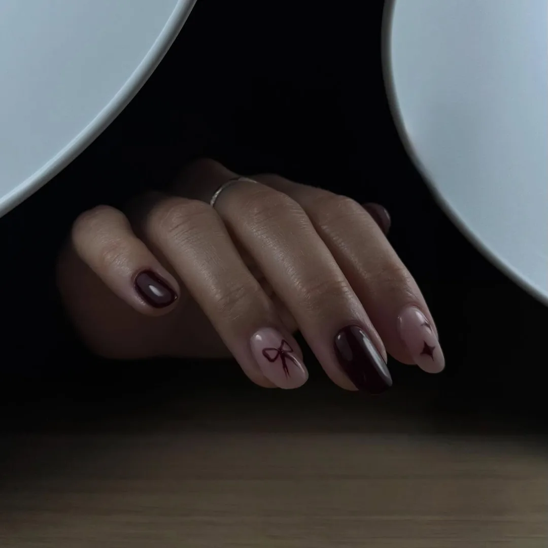Ongles bordeaux et nude, nœud et étoile peints à main levée