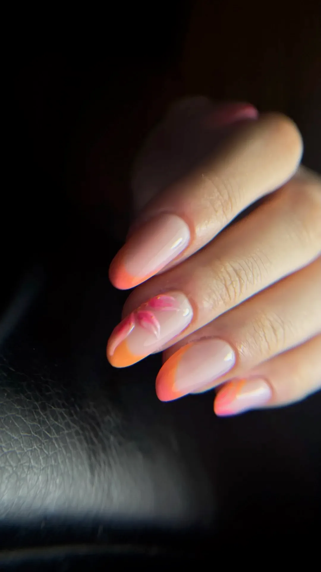Dégradé corail et fleur peinte sur ongles en amande