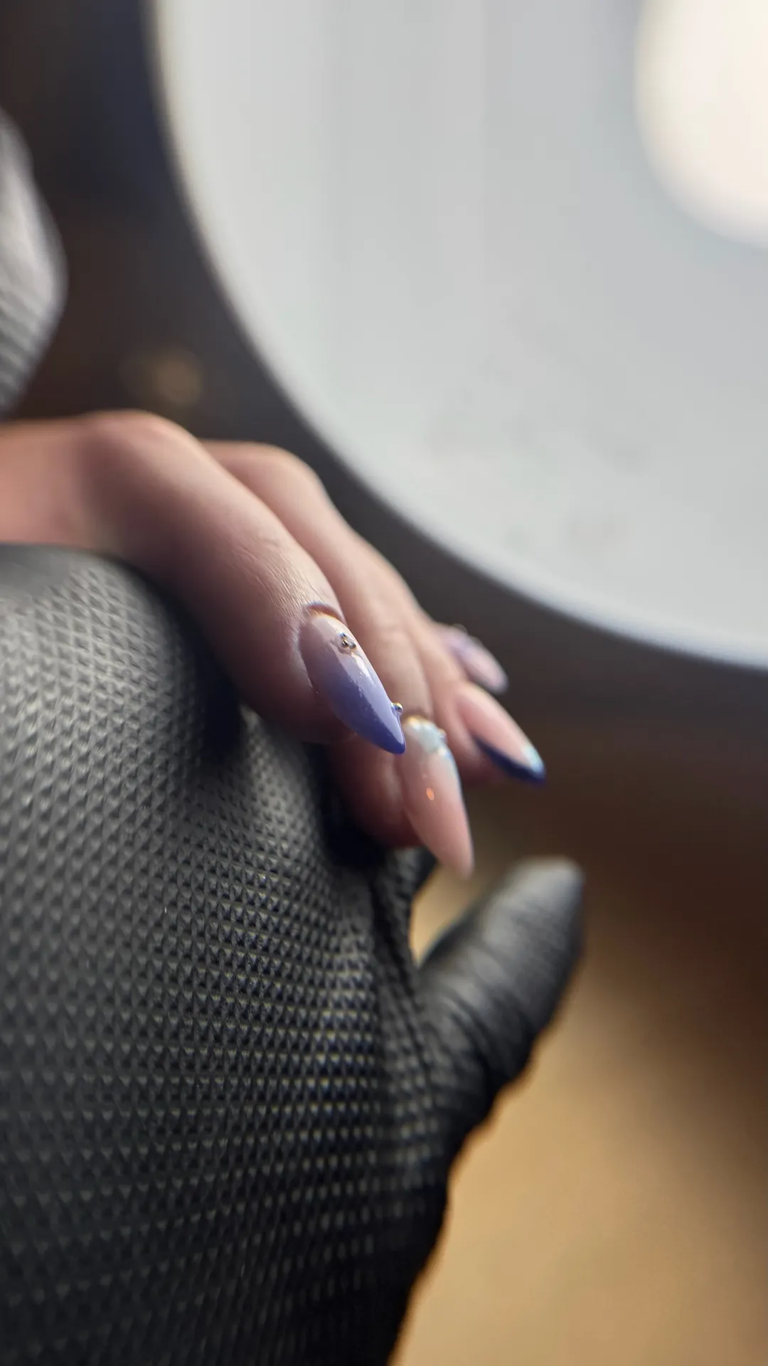 Pose d'ongles violet avec strass et motif floral bleu