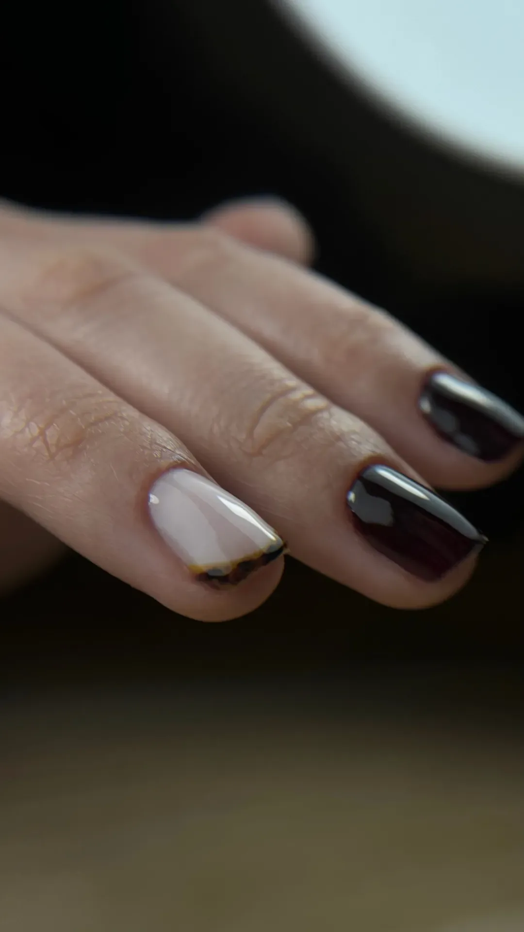 Manucure nude avec un ongle accent foncé et un liseré doré